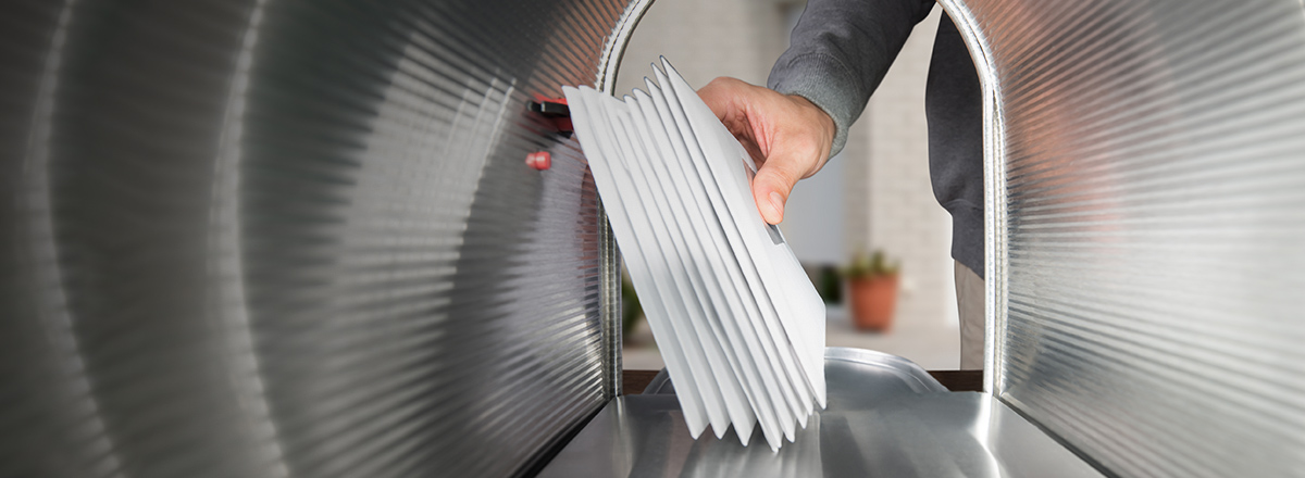 Hand putting envelopes in mailbox