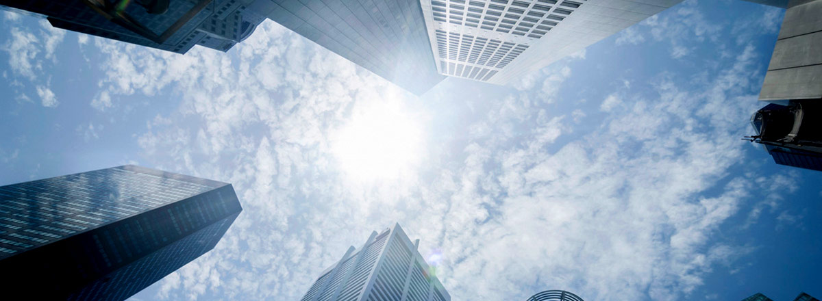 View up at a blue sky with fluffy clouds between several skyscrapers