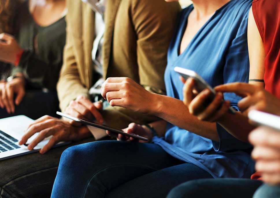 A row of people using laptops and smartphones