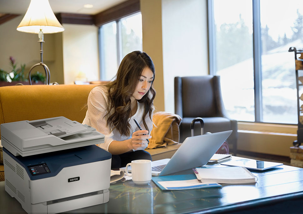 A woman using the Xerox C235 MFP in her home office