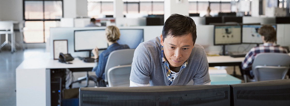 Man using a computer in an office with cubicles