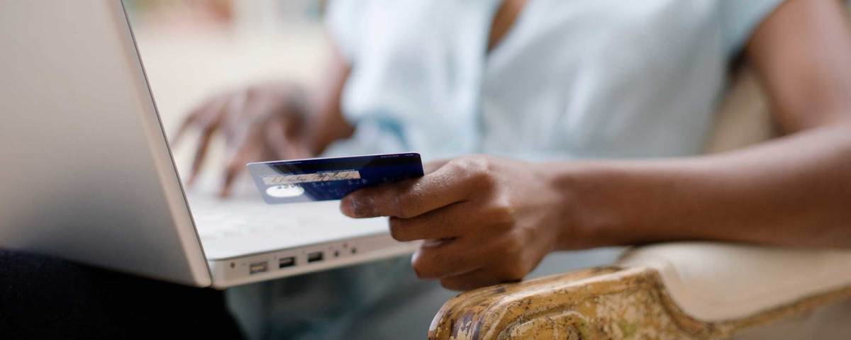 Online shopping - a woman holding a credit card while she uses a laptop