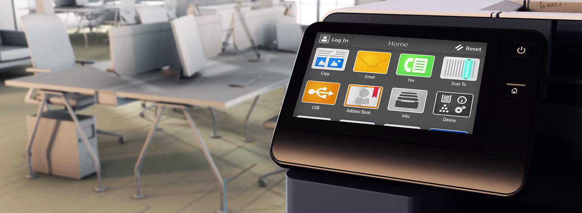 Xerox VersaLink touchscreen with computers on tables in the background