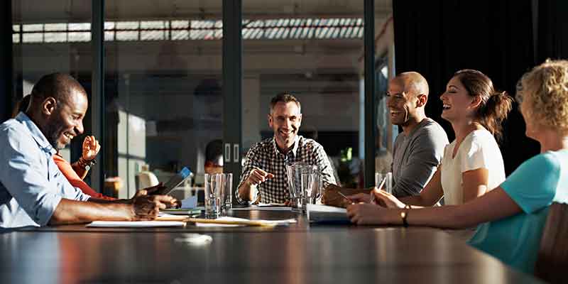 Meeting around a boardroom table with participants laughing