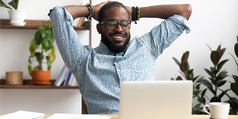 Man sitting at a desking looking at a laptop. 