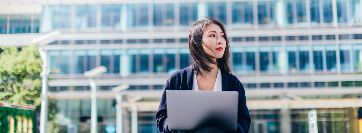 Woman sitting outside office building working on her laptop