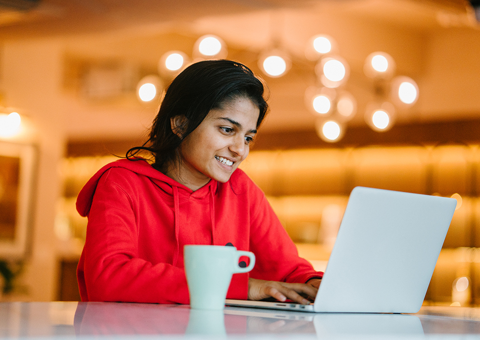 Woman in sweatshirt on lap top in coffee shop.