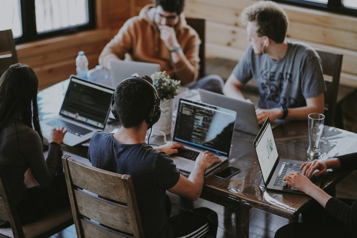 Five people at a table using computers