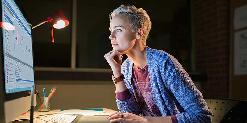 Person in a darkened room peering at a large monitor