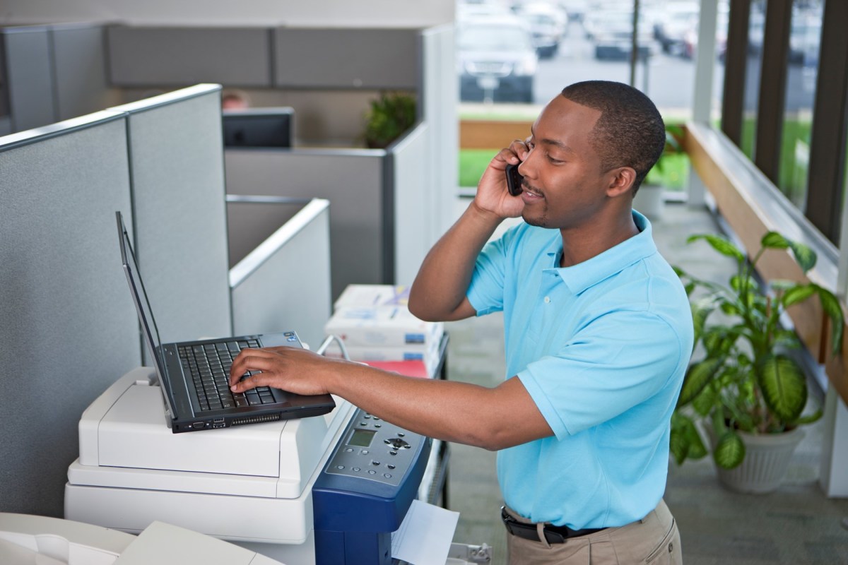 Service engineer working with laptop on Xerox MFP