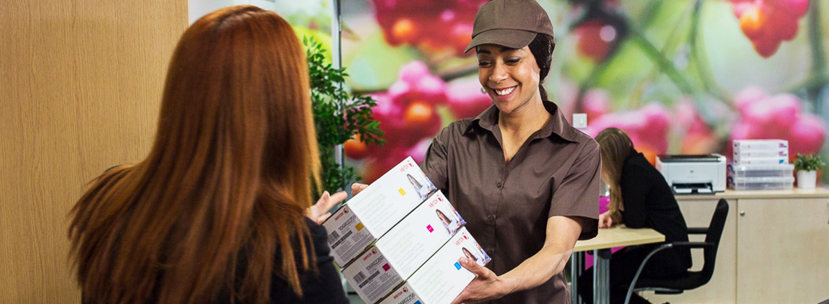 Delivery person handing 3 boxes of Xerox toner to an office manager