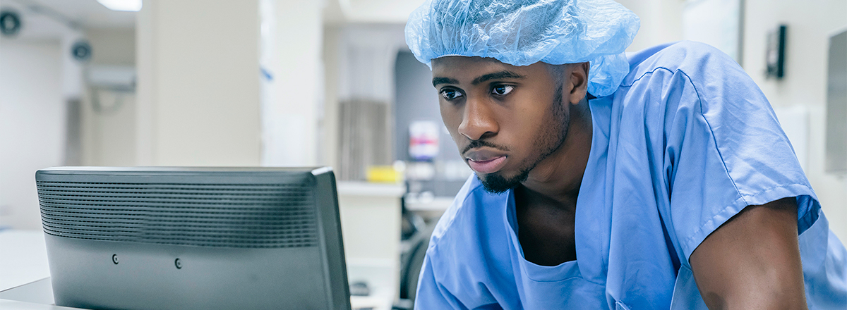 Doctor in scrubs looking at a computer