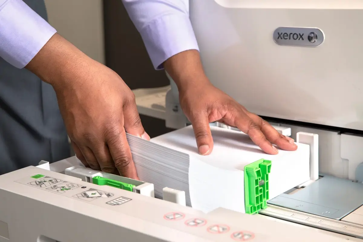 hands loading paper into Xerox MFP