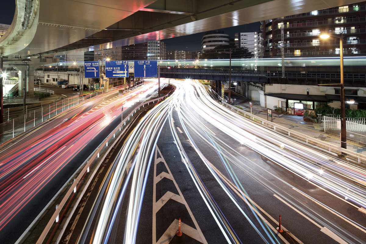 Photo of a highway underpass at night with streaking car headlights and taillights