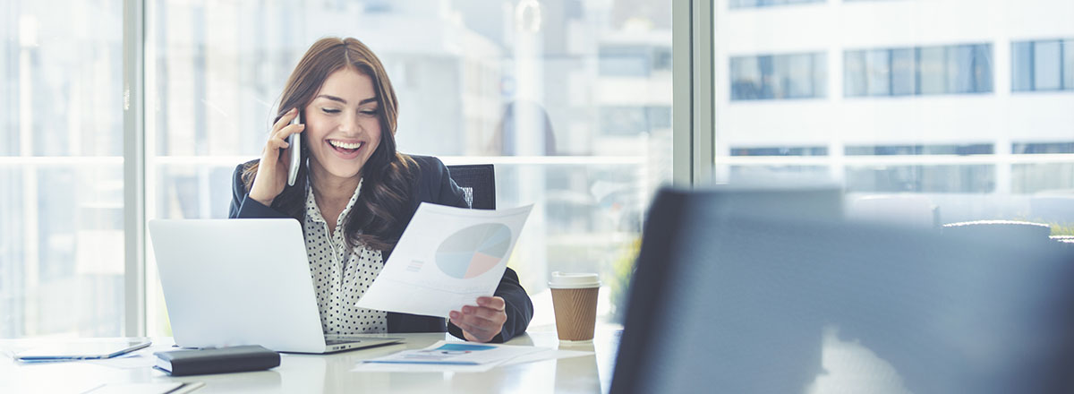 Happy businesswoman looking at a report and talking on the phone