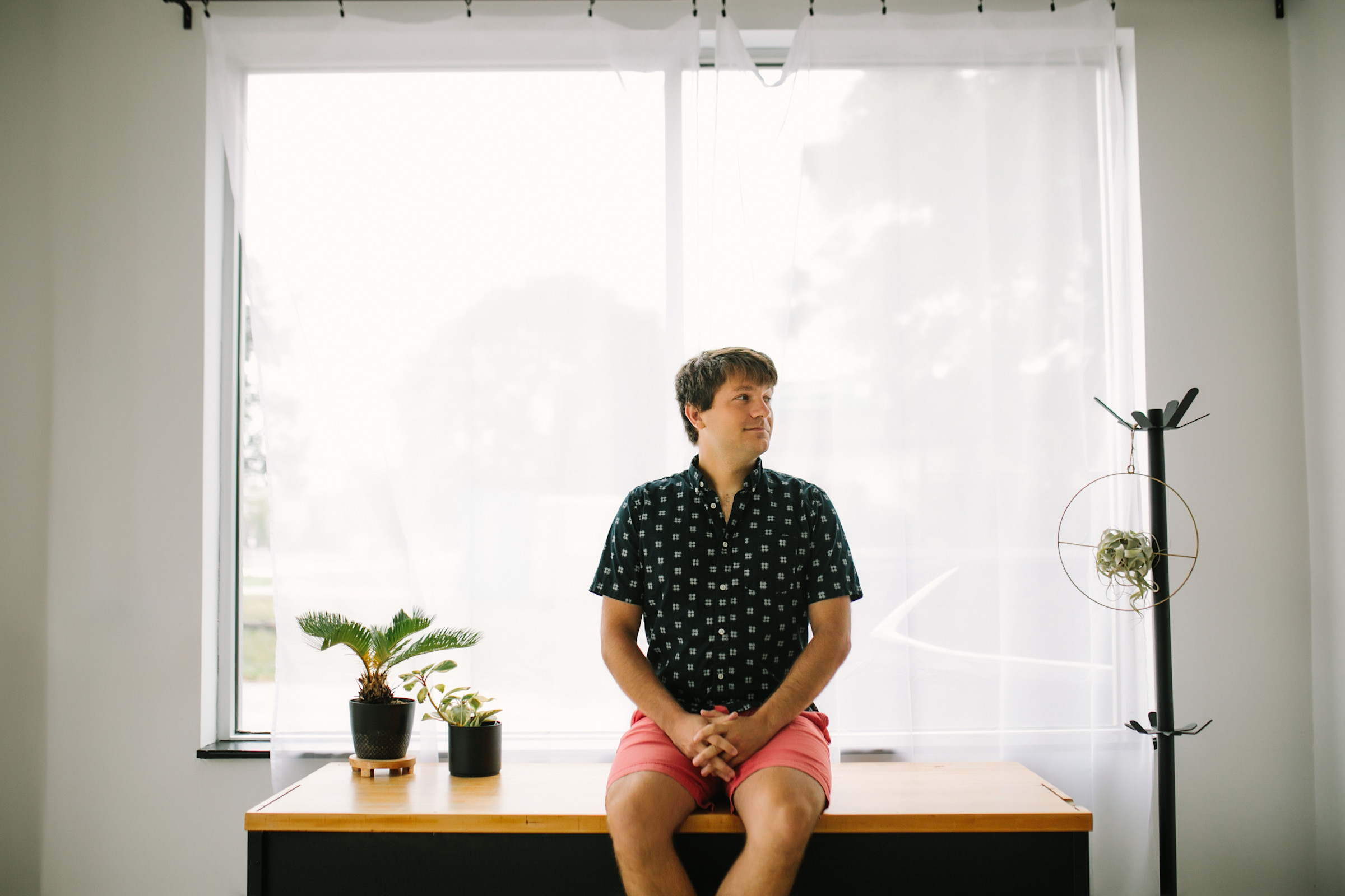 Author Anthony sitting on top of a well-lit desk with various plants