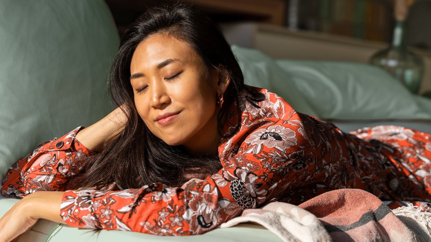 Asian woman meditating in the morning sun for a few minutes in bed