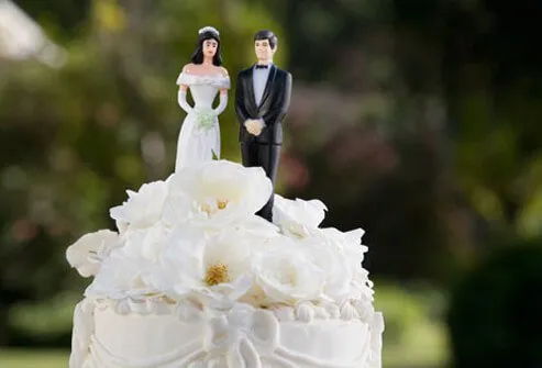 A wedding cake with bride and groom figures on top.