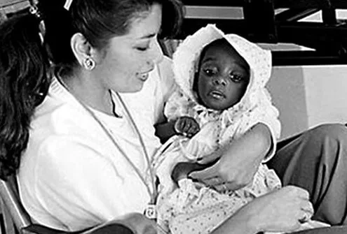 AIDS baby held by hospital worker in 1983.