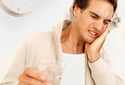 A man experiences tooth sensitivity while drinking ice water.