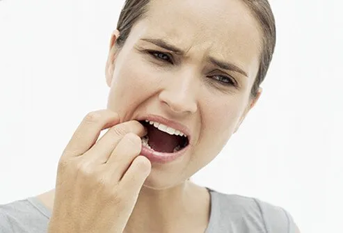 A woman with a toothache feeling her tooth with her finger.