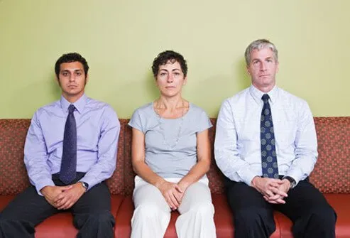 Three very absorbed adults sit next to each other.