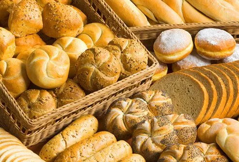 An assortment of fresh breads, rolls, buns, and donuts.