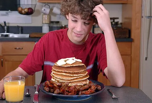 A boy with too many pancakes on his plate questions his breakfast choices.