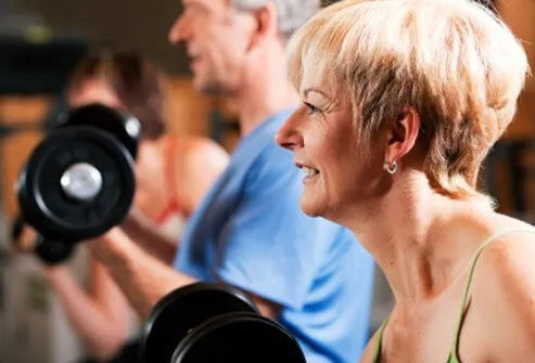 A senior woman and man work out with weights.