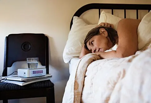 Photo of a woman in bed staring at the clock.