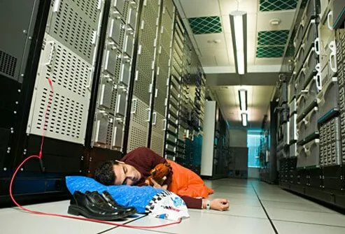 Photo of a network administrator asleep on the floor.