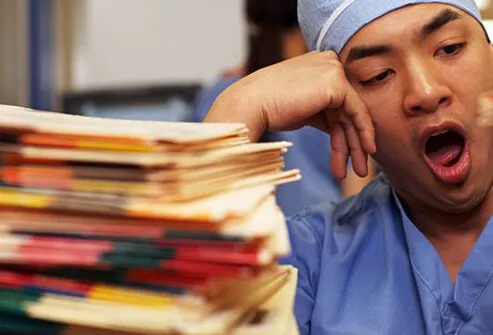 Photo of a nurse yawning over paperwork.