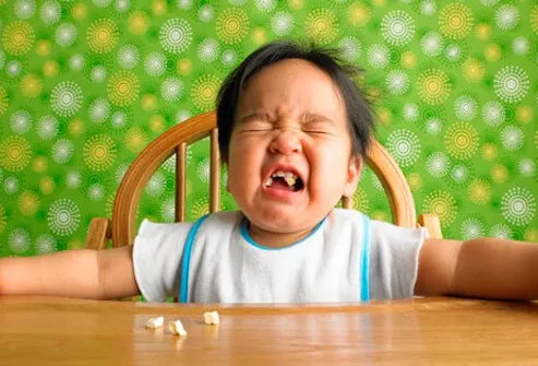 A baby crying in a highchair.