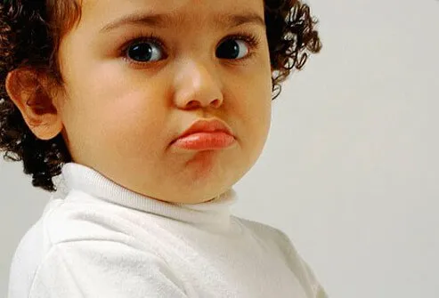 A child pouting in a white shirt.