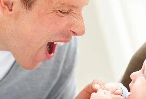 A dad makes funny faces at baby.