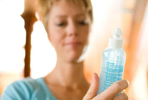 A woman reading saline solution instructions from the bottle.