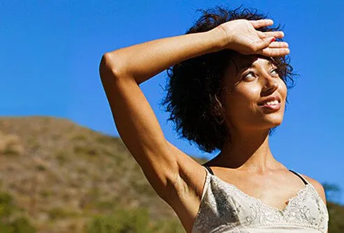 A woman holds her hand up to block the sun. 