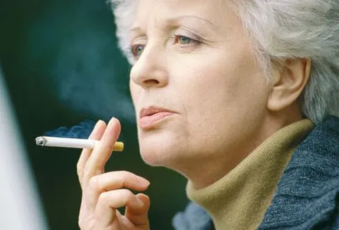 An older woman smoking, increasing her risk of stroke.