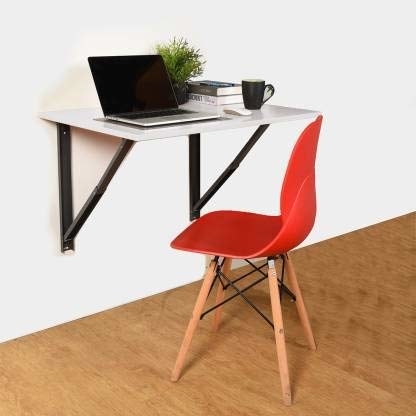 A wall-mounted table with a laptop, coffee mug, and plant on it. There is a red chair near the table.