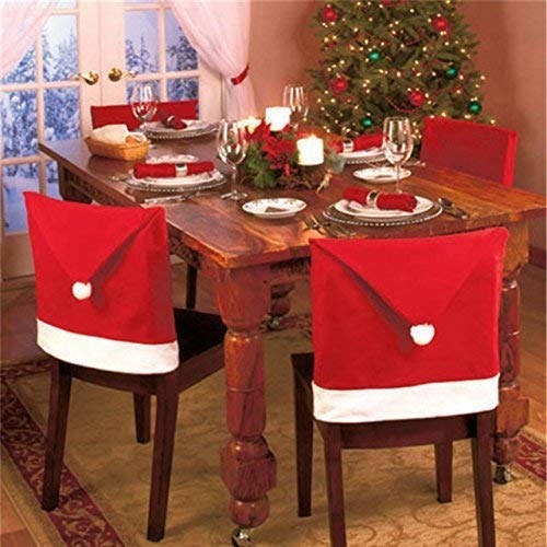 Chairs around a decorated Christmas dinner table adorned with chair covers that resemble a Santa hat.