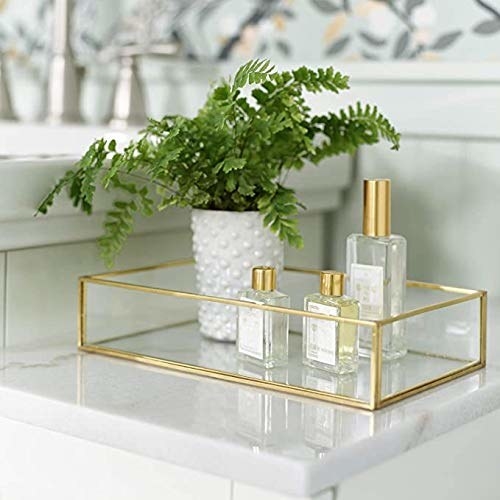 A golden rimmed glass tray with bottles of perfume and a plant in it