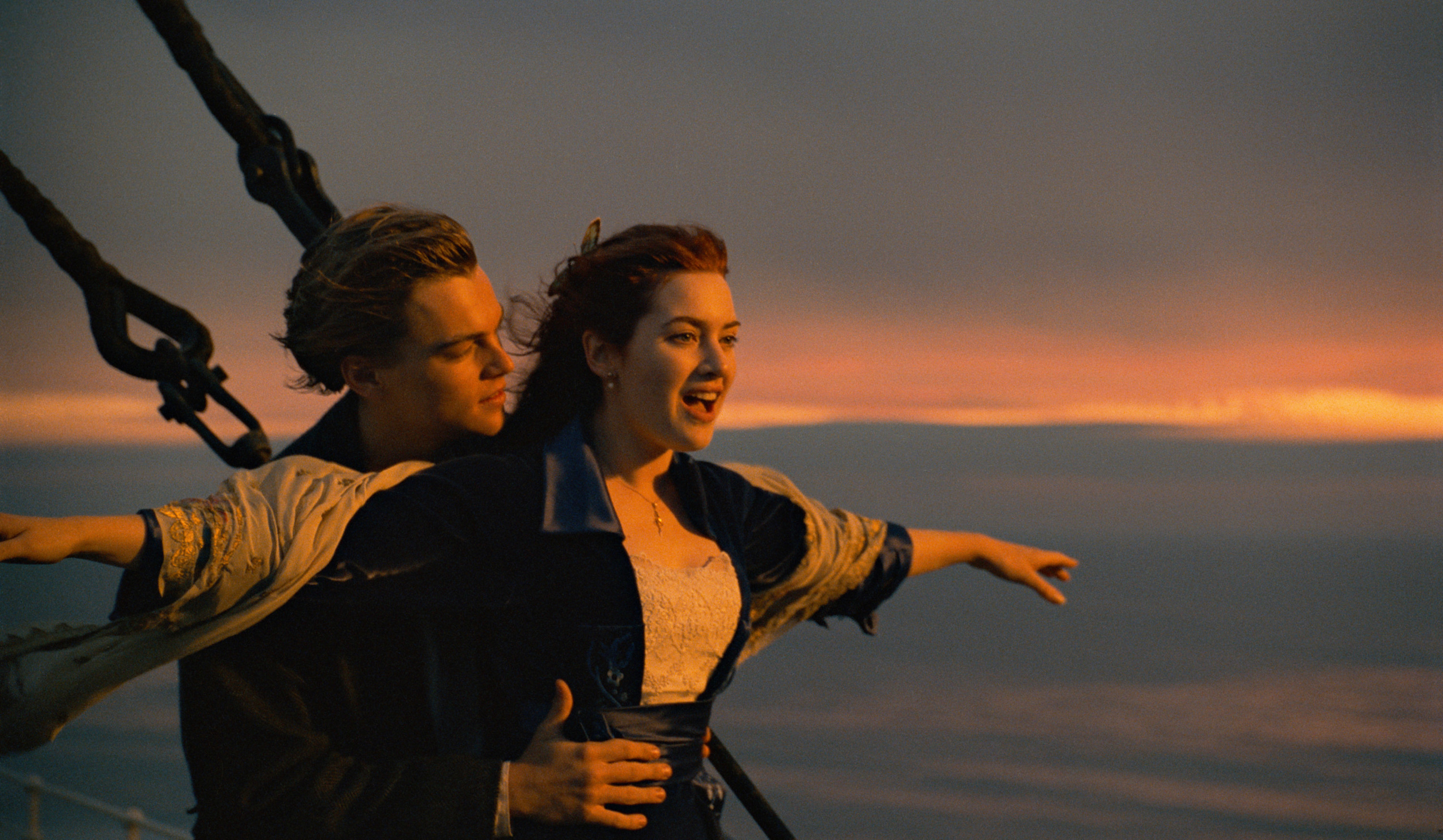 Leo holding Kate Winslet as she spreads her arms open at the front of the Titanic