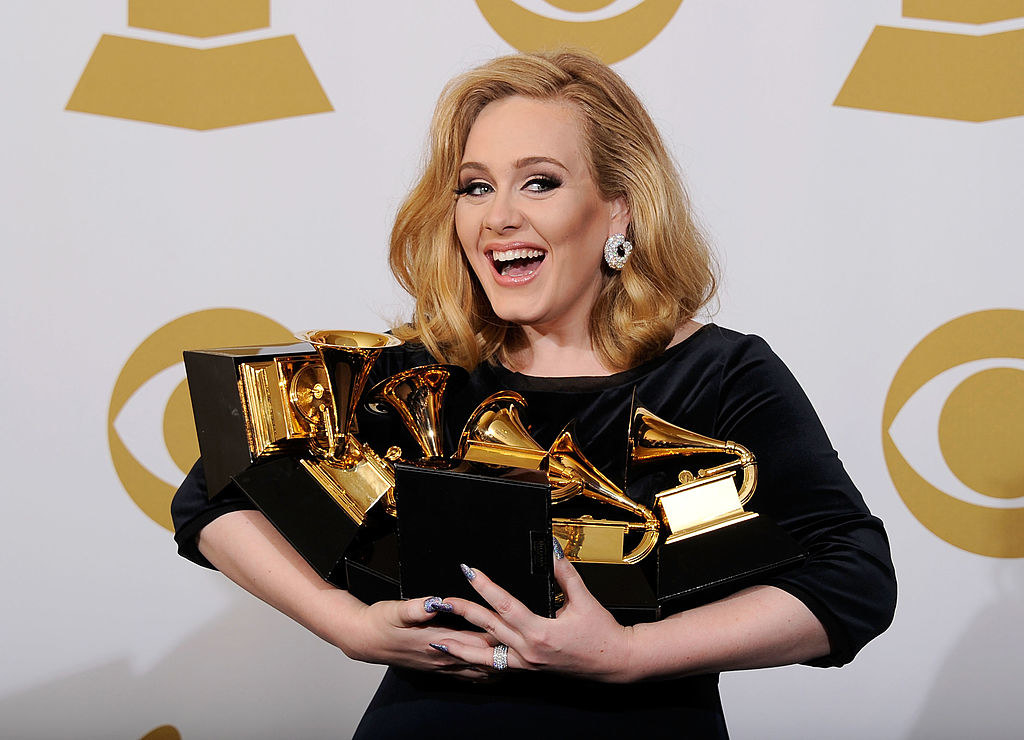 Adele posing while holding all of her Grammys