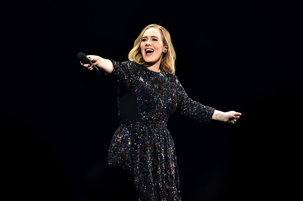 Adele performs onstage in a bejeweled black gown