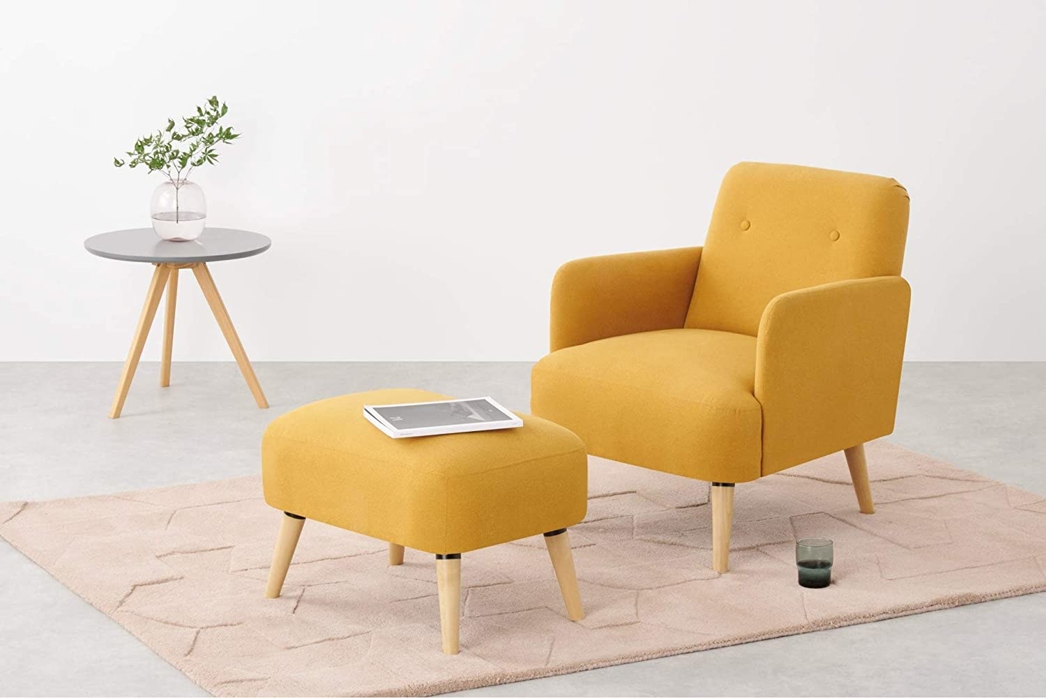 A yellow chair with a yellow footstool near a glass