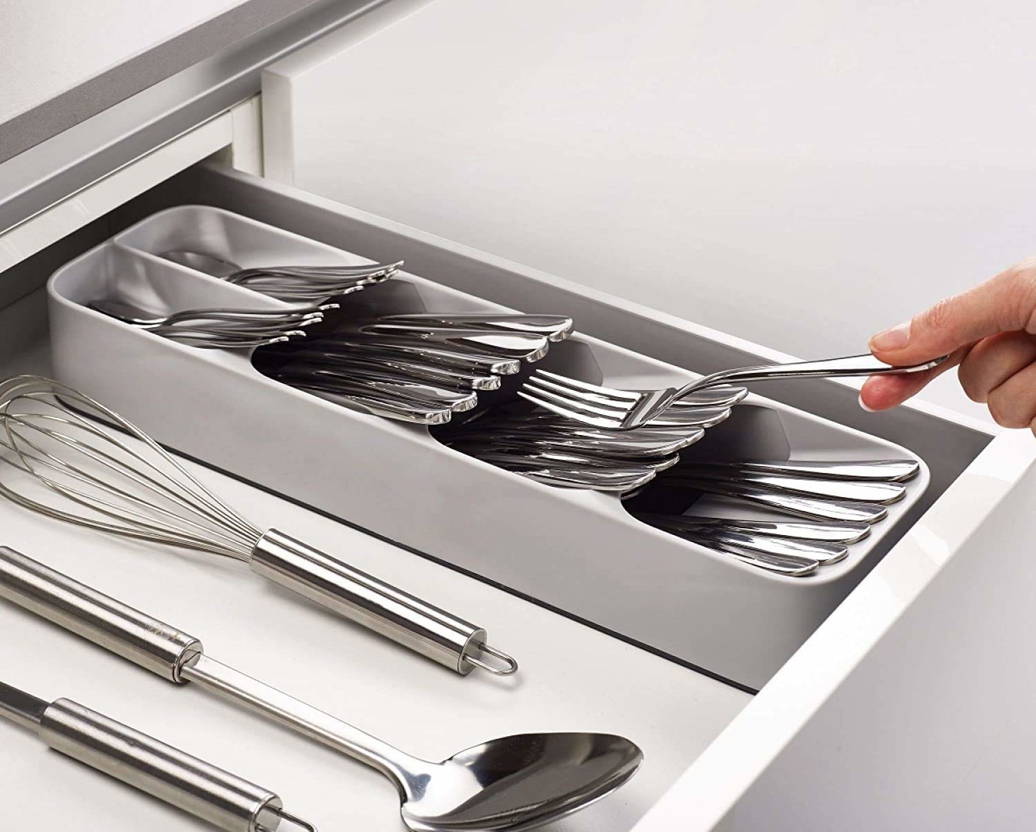 A person adding a fork to a cutlery organiser