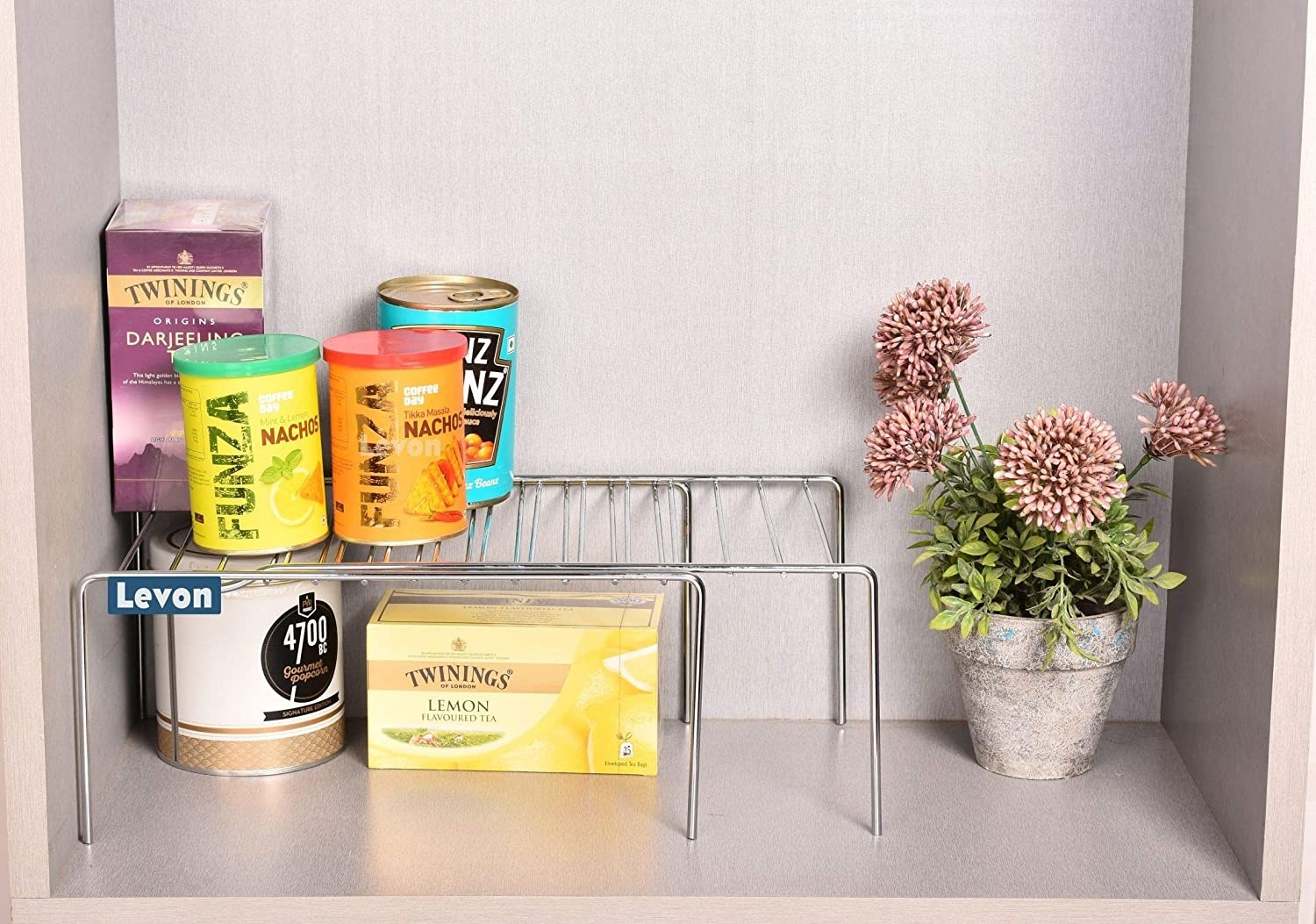 An expandable rack with kitchen food items on it next to a plant