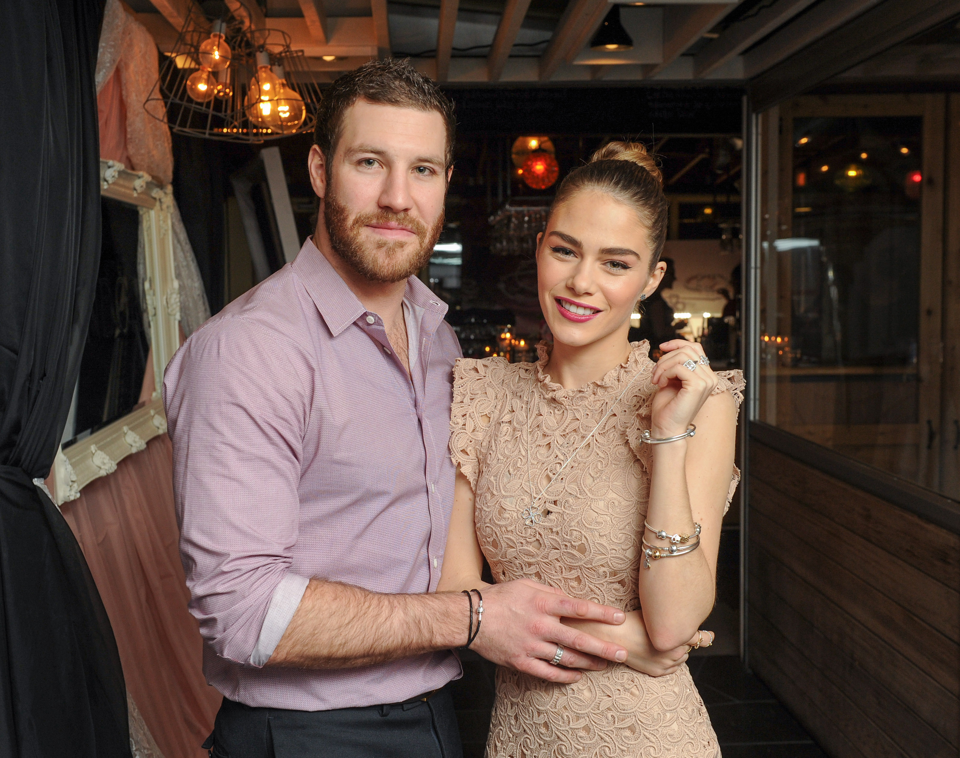 Two people posing for a photo; woman in detailed dress and man in buttoned shirt