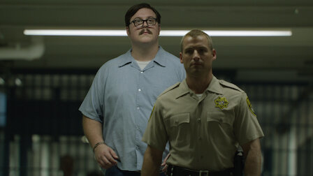 Two characters from the TV series Mindhunter: Ed Kemper (left) in a light blue shirt with glasses and a mustache, and Holden Ford (right) in a police uniform