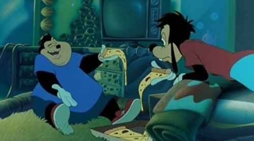 Pete and Goofy eat pizza on a couch in a living room, appearing to be in mid-conversation in an animated scene